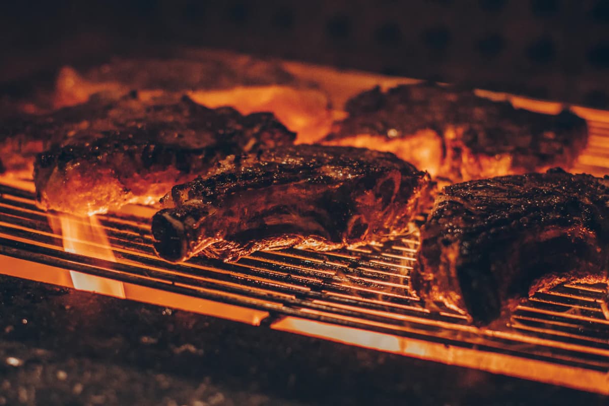 Racks of beef ribs over a wood fire, the grill bars glowing orange