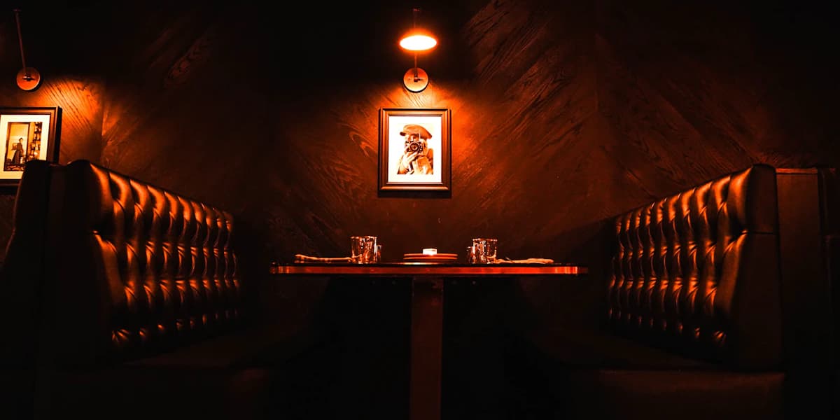 A tufted leather booth lit by a single warm wall lamp