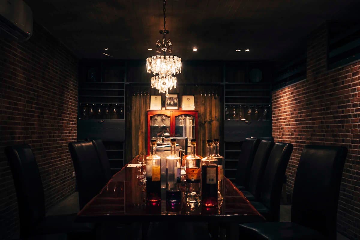The dining room at night: a long table under a chandelier, brick walls and candlelight