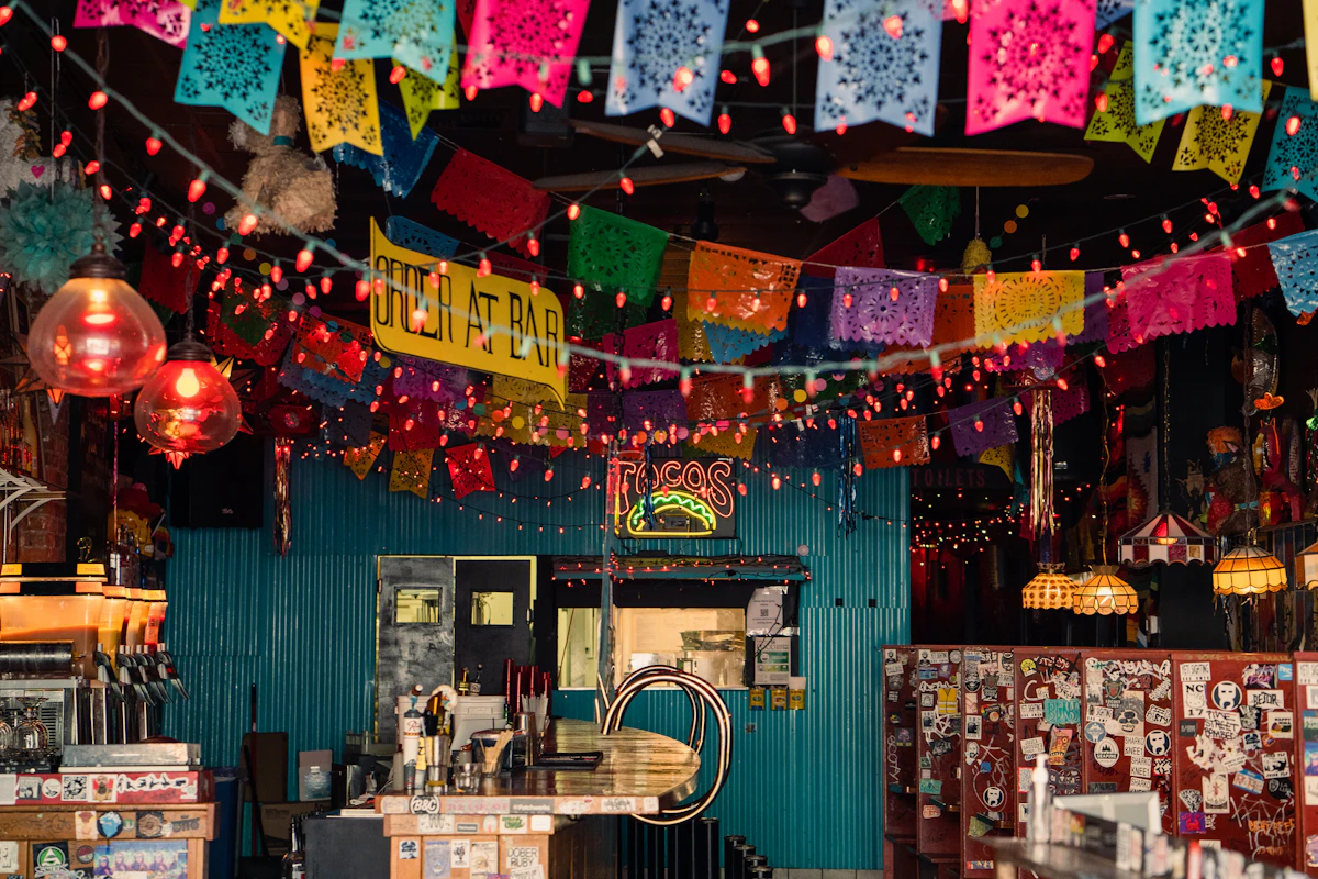 The dining room under strings of papel picado and red lanterns, the bar at the back
