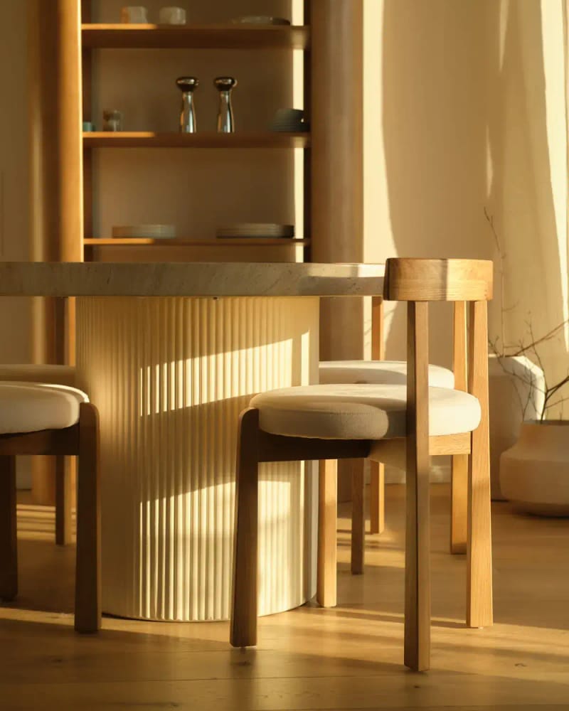 The Ask dining table with a fluted round base, in warm evening light