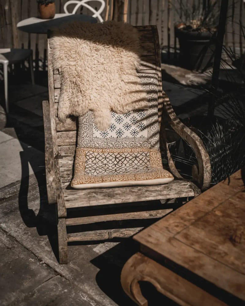 The Fjord lounge chair in the sun with a sheepskin and a woven cushion