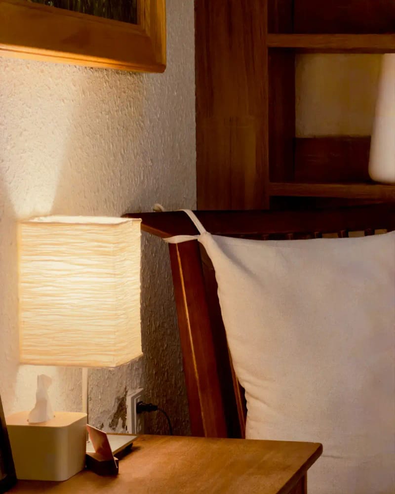 The Ro nightstand beside a bed, a paper lamp glowing on top