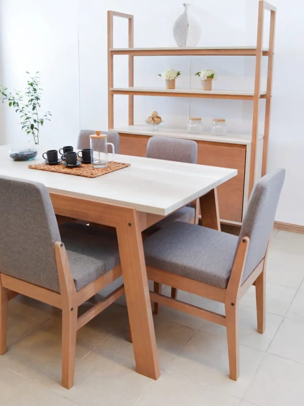 A pale oak dining table with grey upholstered chairs and open shelving