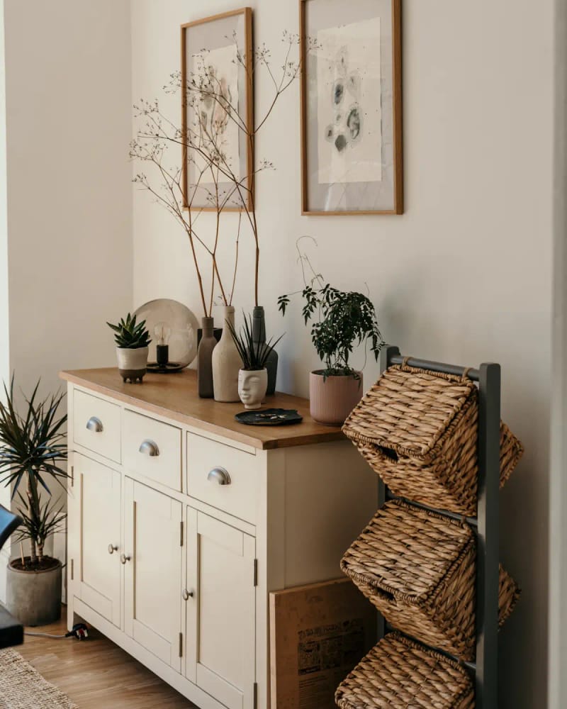 The Tind sideboard in a hallway, with plants and framed botanical prints above it