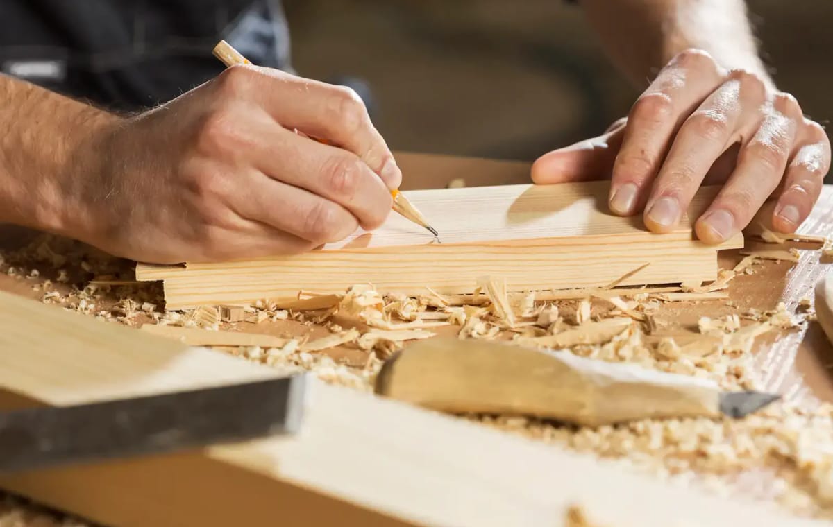 A pencil line being marked on a planed board, wood shavings around it