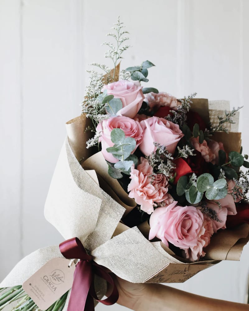 Blush & Bloom: pink garden roses and eucalyptus wrapped in paper with a burgundy ribbon