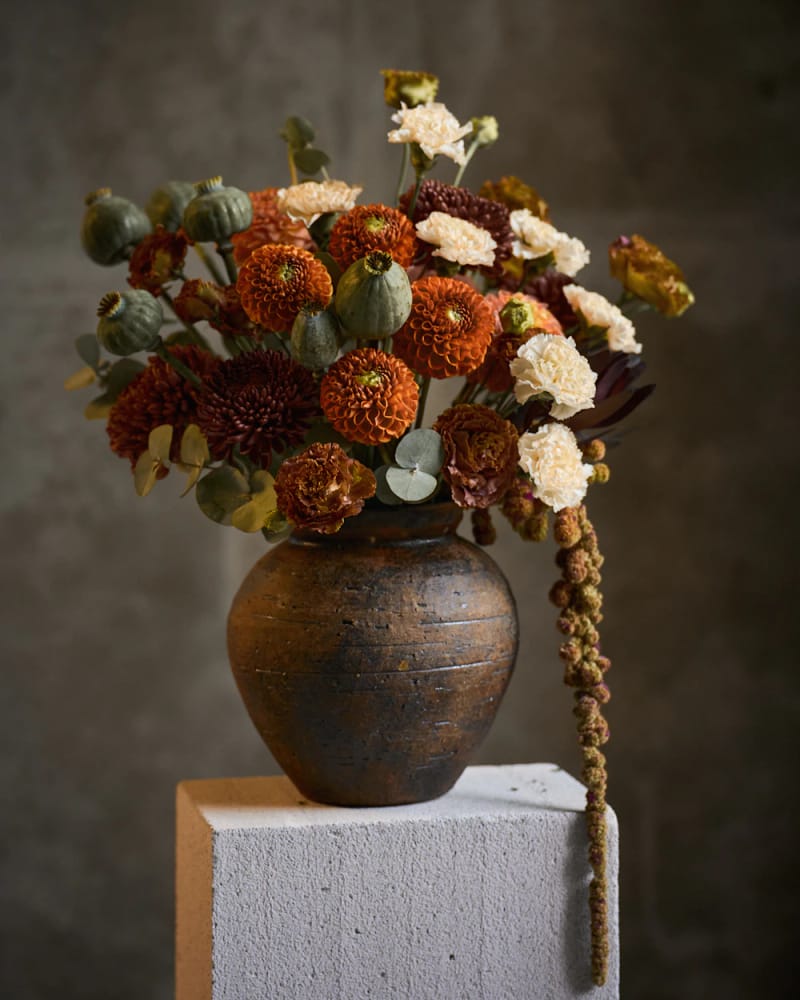 The Wildflower: rust, orange and cream dahlias with seed pods in a stoneware vase