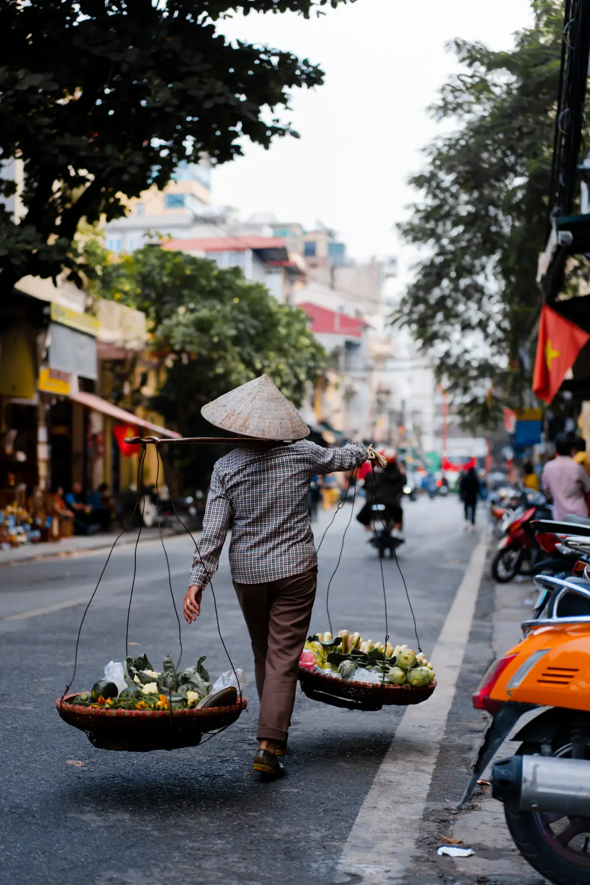 Người bán hàng đội nón lá gánh hàng đi giữa phố cổ Hà Nội