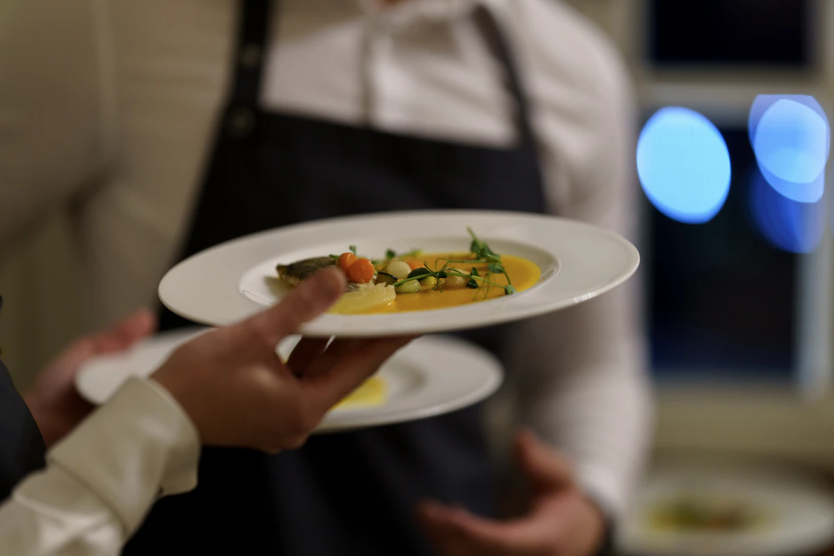 A server carrying two plates of fish across the dining room