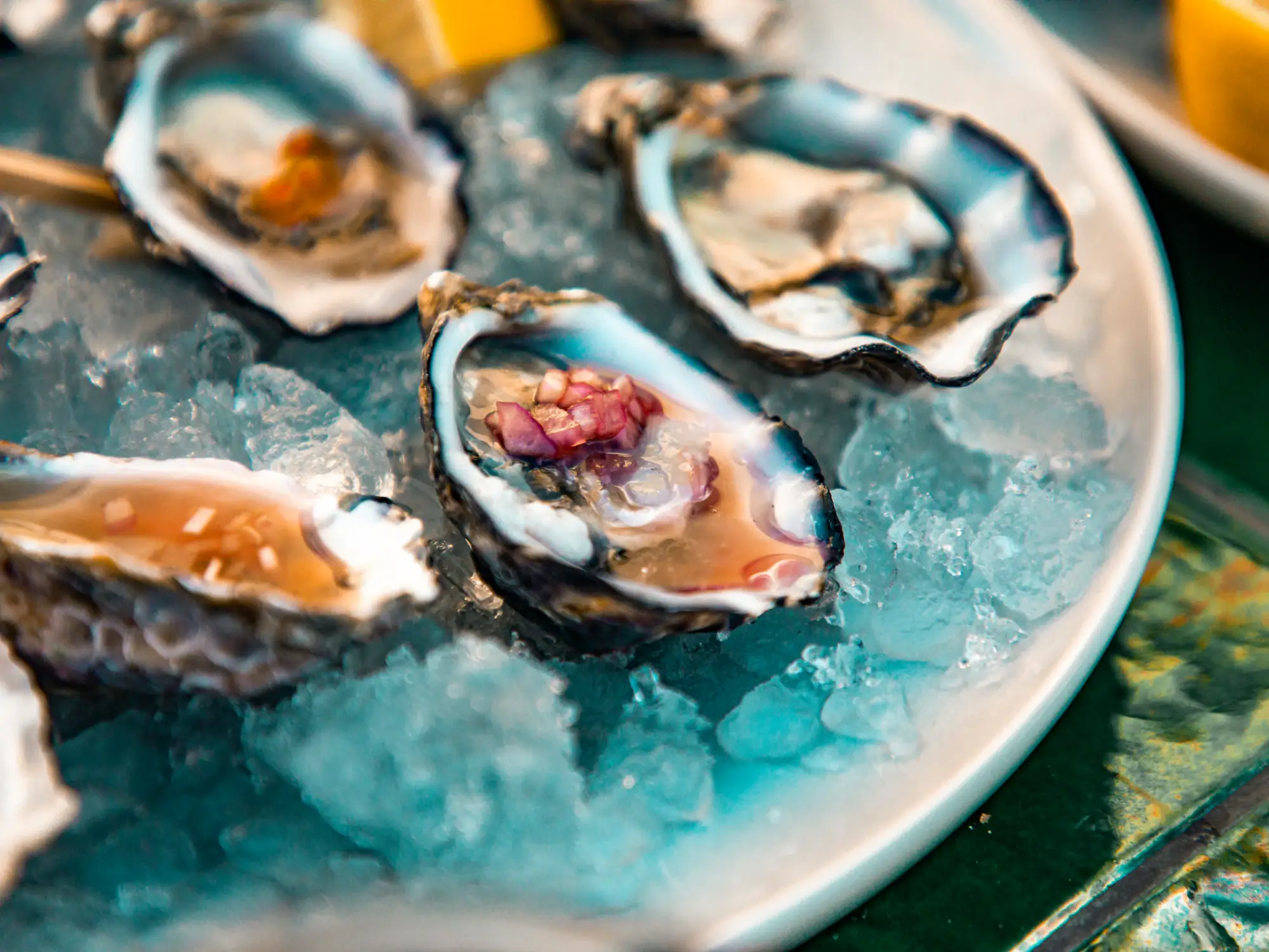 Freshly shucked oysters on crushed blue ice, one topped with a spoonful of mignonette
