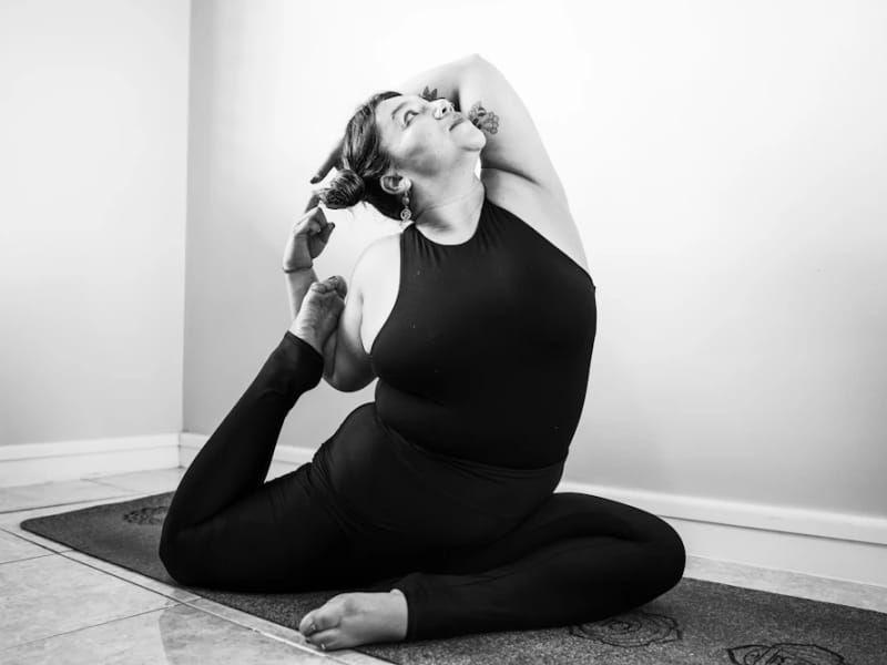 A pregnant woman in a seated twist on a yoga mat, in black and white